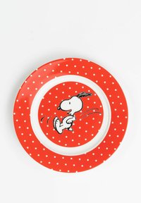 Red plate with white polka dots and a central illustration of a cartoon dog running. Made of ceramic with a glossy finish. Round shape.