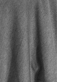 Tissu en laine gris avec un motif à fine couture en chevrons, montrant des plis doux et une texture sous une lumière naturelle.
