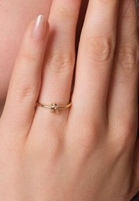 Goldring mit einem kleinen, rechteckigen Stein in einem minimalistischen Design. Der Ringband ist glatt, und der Stein hat eine facettenreiche Klarheit.