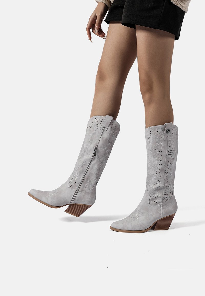 Stivali alti fino al ginocchio in suede sintetico grigio con punta a cono, zip laterale e dettagli ritagliati decorativi; tacco impilato effetto legno.
