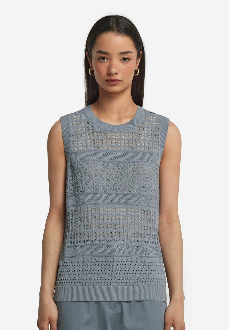 Ljust blå stickad ärmlös topp med strukturerade mönster och öppna mesh-designs. Ribbad halsringning och nederkant ger struktur.