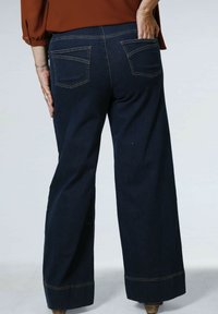 Pantalons larges en denim bleu foncé avec taille haute, dotés de deux poches arrière et finis avec des coutures contrastées le long de l'ourlet.