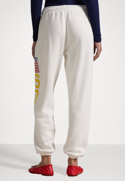 Λευκές φόρμες με ελαστική ζώνη και μανσέτες, με πολύχρωμο γραφικό σχέδιο μιας αμερικανικής σημαίας και το "ΗΠΑ" στο αριστερό πόδι.