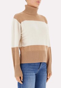 Maglione a collo alto a righe marroni e crema con colletto e polsini a costina. Texture morbida, design cropped e vestibilità rilassata.