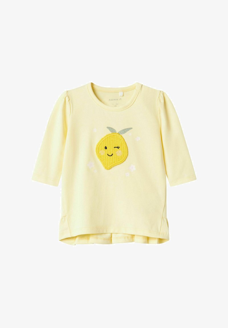 Geltonas ilgomis rankovėmis marškinėliai su besišypsančia citrina aplikacija, gėlių akcentais ir apvaliu iškirpimu. Minkšta medvilnė su susiraukšlėjimais rankovėse.