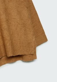 Détail d'un pull marron en tricot présentant une texture douce, un ourlet côtelé et des fentes latérales, mettant en valeur une silhouette décontractée.