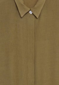 Chemise marron texturée à boutons, avec col et un bouton blanc visible en haut au centre.