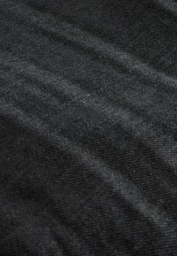 Tejido negro texturizado con una sensación suave y ligeramente áspera. Presenta estrías sutiles y una superficie lisa y uniforme. Ideal para prendas de vestir o tapicería.