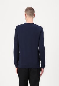 Sudadera azul marino de manga larga, con puños y dobladillo acanalados. Textura suave, diseño de cuello redondo y silueta ajustada. Estilo simple y minimalista.