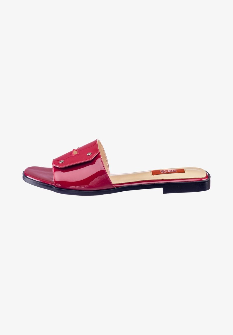Sandale à semelle plate en cuir verni rouge avec un accent en rabat, quincaillerie argentée, design à bout ouvert et semelle noire plate. Fini lisse et style moderne.