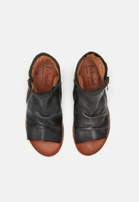 Sandalias de cuero negro con una textura suave y arrugada, diseño de punta abierta y plantilla de cuero marrón. Presentan detalles con cremallera en los laterales.