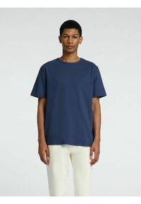 Marinblå T-shirt med rund hals i mjukt och glansigt tyg, med korta ärmar och en avslappnad passform. Enkel design, utan synliga mönster eller detaljer.