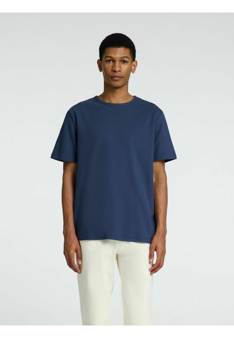 Marinblå T-shirt med rund hals i mjukt och glansigt tyg, med korta ärmar och en avslappnad passform. Enkel design, utan synliga mönster eller detaljer.