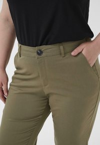 Olijfgroene broek met een rechte pasvorm, voorzien van een knoopsluiting, riemlussen en zijzakken. Soepele stofstructuur.