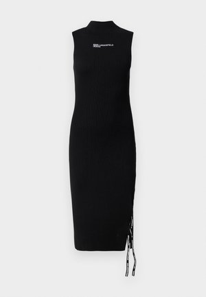 Rochie neagră, cu model cu nervuri, de lungime până la genunchi, cu gât înalt. Prezintă slituri laterale și șnururi cu accente logo. Fără mâneci.