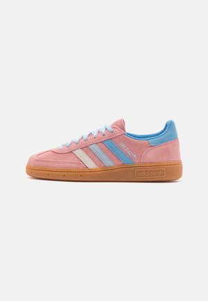 Niskie buty sportowe Adidas z różowego zamszu z niebieskimi i białymi paskami, gumową podeszwą, niebieską wkładką i oznaczeniem „Spezial” na boku.