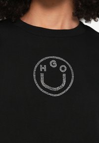 Μαύρο φούτερ με λογότυπο χαμογελαστής φατσούλας διακοσμημένο με κρύσταλλα, γράμματα "N" και "G", στρογγυλή λαιμόκοψη και ριμπ ύφανση.