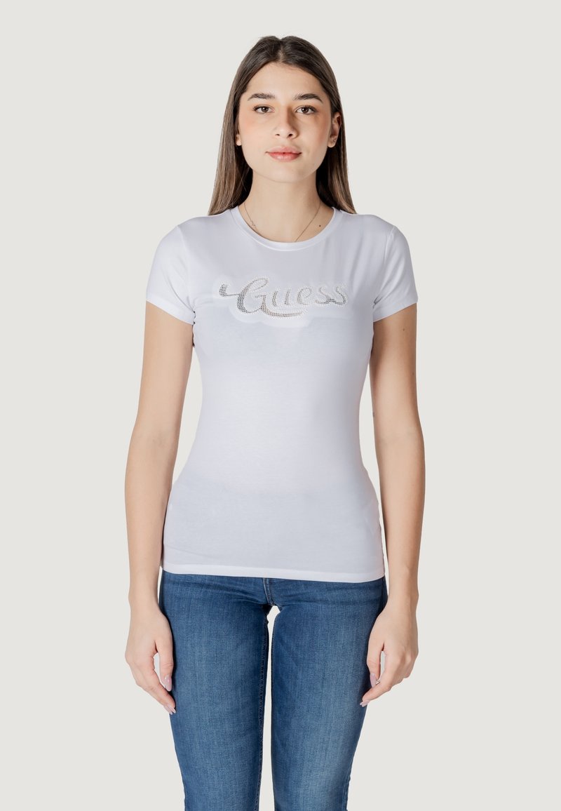 Witte aansluitende t-shirt met korte mouwen, voorzien van een zilveren rhinestone 'Guess' logo over de borst. Zacht katoenen materiaal.