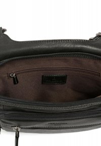 Interno di una borsa a tracolla nera in pelle, con un rivestimento marrone scuro, una tasca con zip e un'etichetta. La chiusura a zip è visibile.