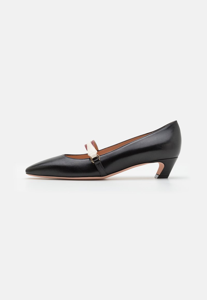 Black leather pump with pointed toe and a low, angled heel. Features a strap with a metallic buckle and a contrasting accent. Smooth texture.