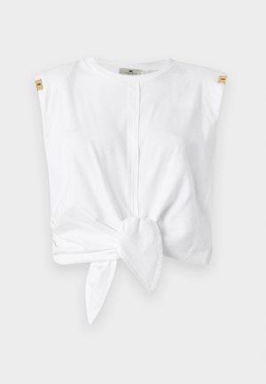 Top alb cu mâneci scurte din bumbac, cu detaliu nod în față. Prezintă accente pe umeri și decolteu rotund. Textură netedă.