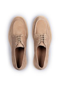 Scarpe in suede beige con punta arrotondata, cuciture bicolore e design con lacci. Texture liscia con suola piatta in gomma leggera.