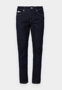Dark blue denim jeans with a slim fit, five pockets, traditional stitching, and a metal button closure at the waistband. Crisp texture.