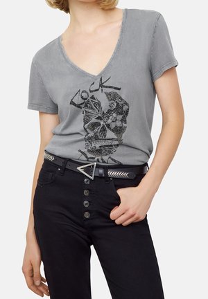 Gray cotton t-shirt with a deep V-neck and black graphic design featuring a skull. Worn with black pants and a triangular silver buckle belt.