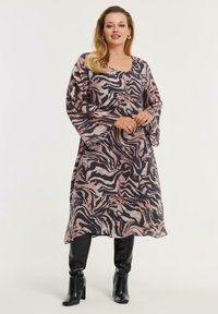 Langärmliges Kleid mit einem pinken und schwarzen Zebra-Muster, aus leichtem Stoff gefertigt; hat eine lässige Passform und einen runden Ausschnitt. Wird mit kniehohen Stiefeln getragen.