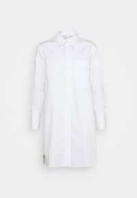 Abito camicia bianco a maniche lunghe con bottoni, colletto e taschino sul petto, esposto su uno sfondo bianco semplice.