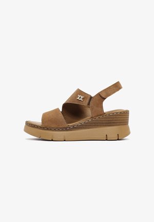 Zeppa in suede tan con cinturino regolabile, punta aperta e accento con logo argentato. Presenta una piattaforma texturizzata e dettagli di cucitura.