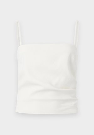 Λευκό κοντό τοπ χωρίς μανίκια με λεπτές τιράντες, τετράγωνο ντεκολτέ και διακριτικές ανοιγμένες λεπτομέρειες ύφασματος.