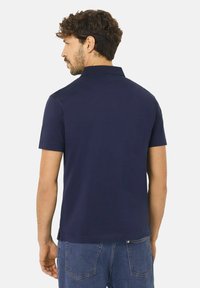 Marinblå kortärmad pikétröja med klassisk krage, tillverkad av mjuk och slät väv, med rak fåll och utan synliga logotyper.