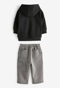 Sort hættetrøje med kengurulomme, parret med grå og hvide stribede shorts med elastisk talje og sidelommer.