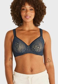 Marine kant beha met bloemmotieven, doorschijnende stof, beugelsupport en verstelbare bandjes. Goudkleurig decoratief detail in het midden.