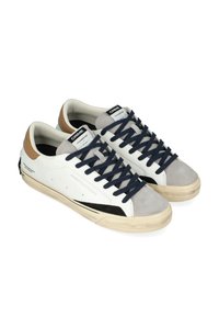 Sneakers in pelle bianca con punta in suede grigia e dettagli neri. Lacci blu navy, accenti sul tallone color sabbia e suola in gomma testurizzata.