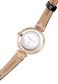 Fondo de reloj redondo de acero inoxidable con cubierta de vidrio, acentos en oro rosa, correa de cuero genuino beige y detalles de la marca grabados.