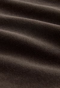 Tela texturizada de color marrón oscuro con un patrón de acanalado visible, que muestra pliegues suaves y ondulados y un acabado liso.