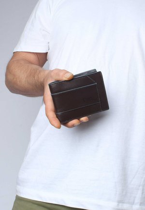 Braune Ledergeldbörse, die in einer Hand gehalten wird, mit hellblauem Nähen und einem geprägten Logo. Kompakte Design mit Kartenfächern.