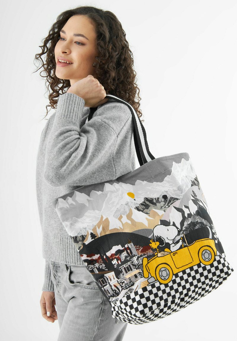 Leinen-Tote-Bag mit einem malerischen Bergdruck, einem Comic-Hund in einem gelben Auto und einem karierten Muster am unteren Rand. Schwarze Griffe.
