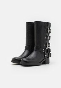 Black leather ankle boots featuring a rounded toe, mid-heel, and multiple silver-tone buckles along the sides. Smooth texture with minimal detailing.