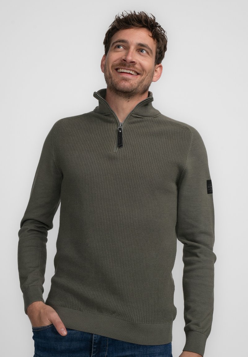 Olivgrüner Zip-Pullover mit strukturiertem Muster, langen Ärmeln und gerippten Bündchen. Verfügt über ein kleines Emblem am linken Arm.