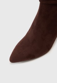 Smeđe antilop čizme do gležnjeva s uskim vrhom, s glatkom teksturom i elegantnim dizajnom. Peta nije vidljiva u ovom planu blizu.