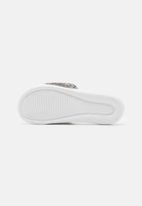 Semelle de sneaker blanche avec un motif texturé. Présente une surface lisse et un design courbé. Marquage subtil visible sur la semelle.