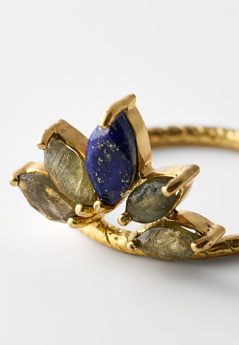 Goldring mit einem zentralen blauen Lapislazuli-Stein, flankiert von drei markasitenförmigen Labradoritsteinen, und einem strukturierten Band.
