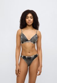 Schwarzes Bralette- und Tanga-Set im Denim-Stil mit verstellbaren Trägern, dreieckigem Design und einem Logo-Band. Glatte Textur mit verwaschenen Akzenten.