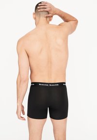 Calzoncillos negros con una banda elástica que presenta el nombre de la marca "Resteruds" en blanco. Se ven ajustados y tienen una textura suave.