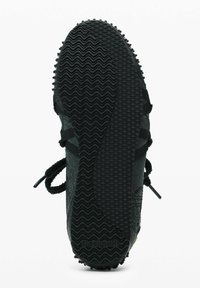 Sort sneakersål med bølgede og diamantformede mønstre, synlige snørebånd, og "Desigual" logo nær hælen på en hvid baggrund.