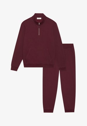 Burgundy pullover with high collar and half zip, featuring front pocket; matching tapered pants with elastic waistband and side pockets.