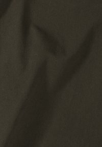 Tissu vert olive foncé avec texture en sergé diagonal et plis subtils créant des ombres et des reflets doux.